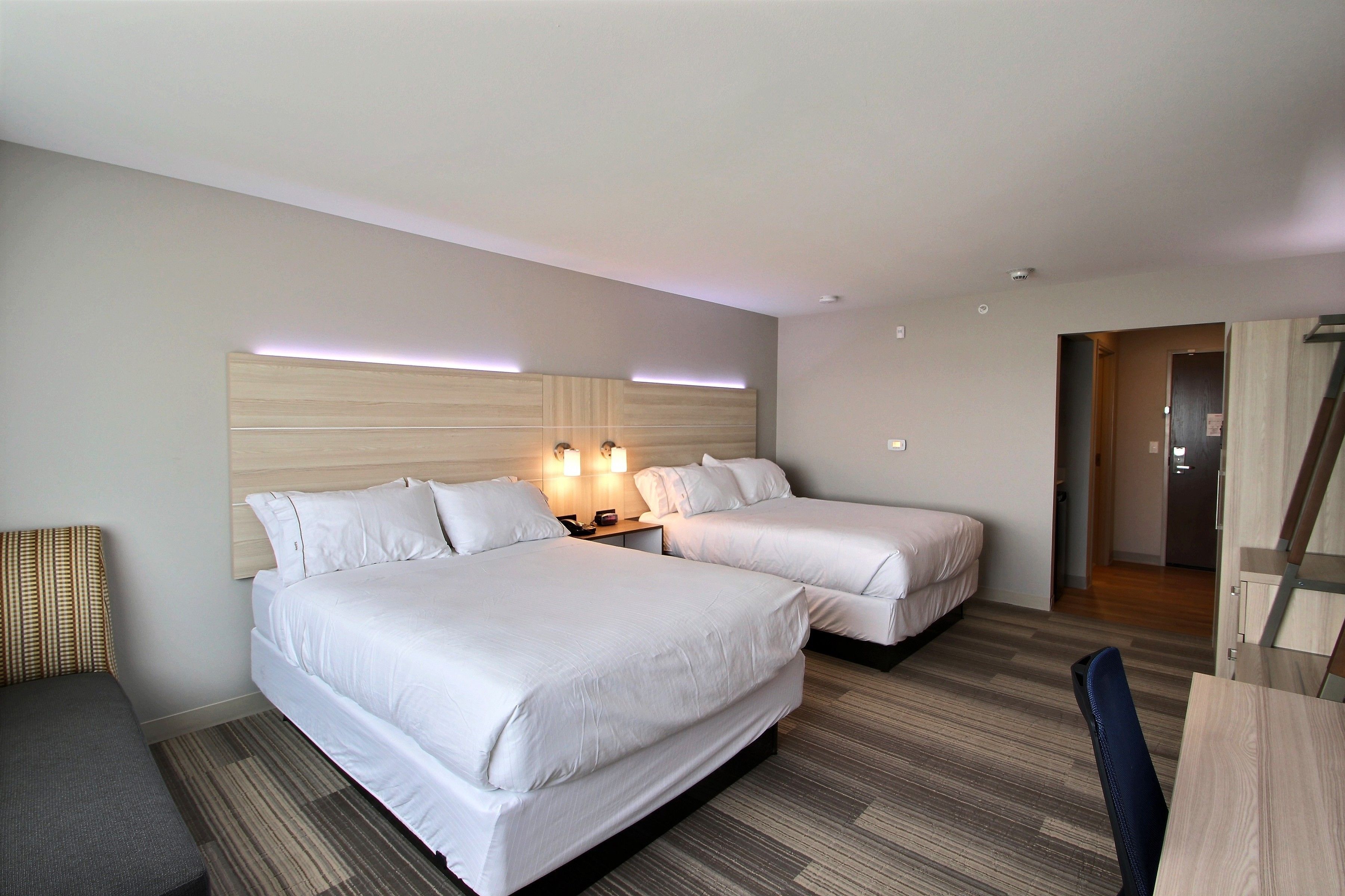 A hotel room with two beds, a desk, and a chair.