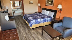 A hotel room with a bed, a desk, a chair, and a small table. - Budget Inn (Eastland)