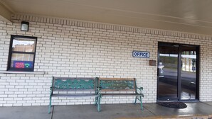 A brick building with a bench in front, a sign reading "OFFICE", and a digital display above the bench. - Budget Inn (Eastland)