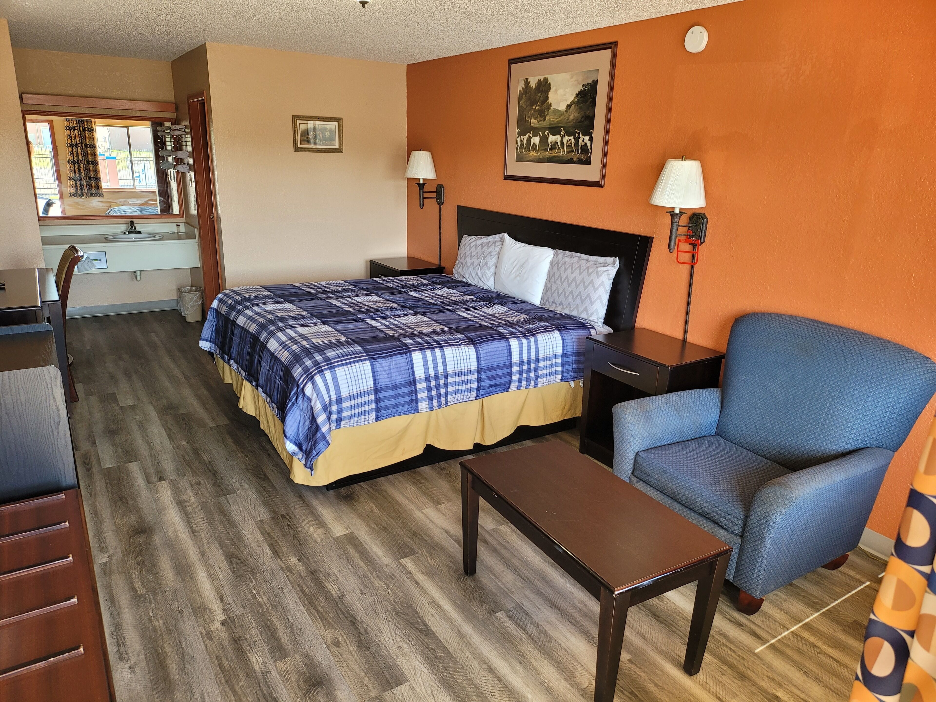 A hotel room with a bed, a desk, a chair, and a small table.