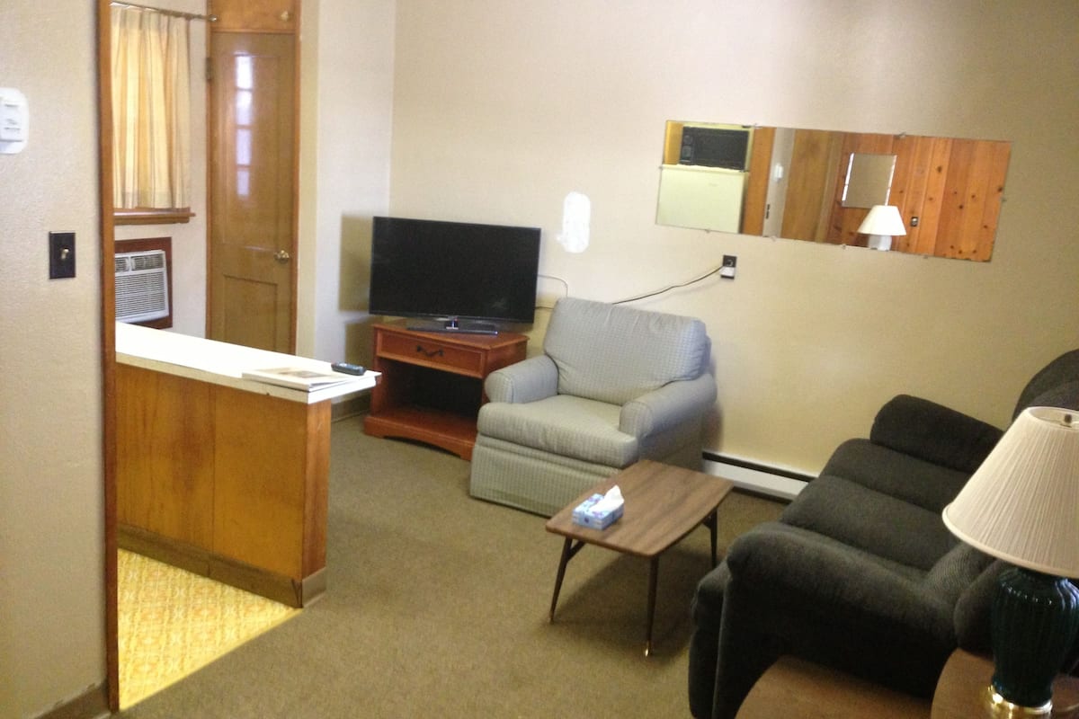 A compact living room with a television, a sofa, a chair, and a small table.