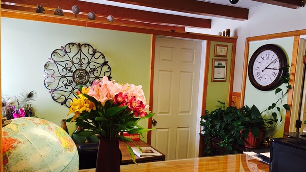 A reception desk with a globe, a vase of flowers, and a clock on the wall. - Jamestown Motel (Jamestown)