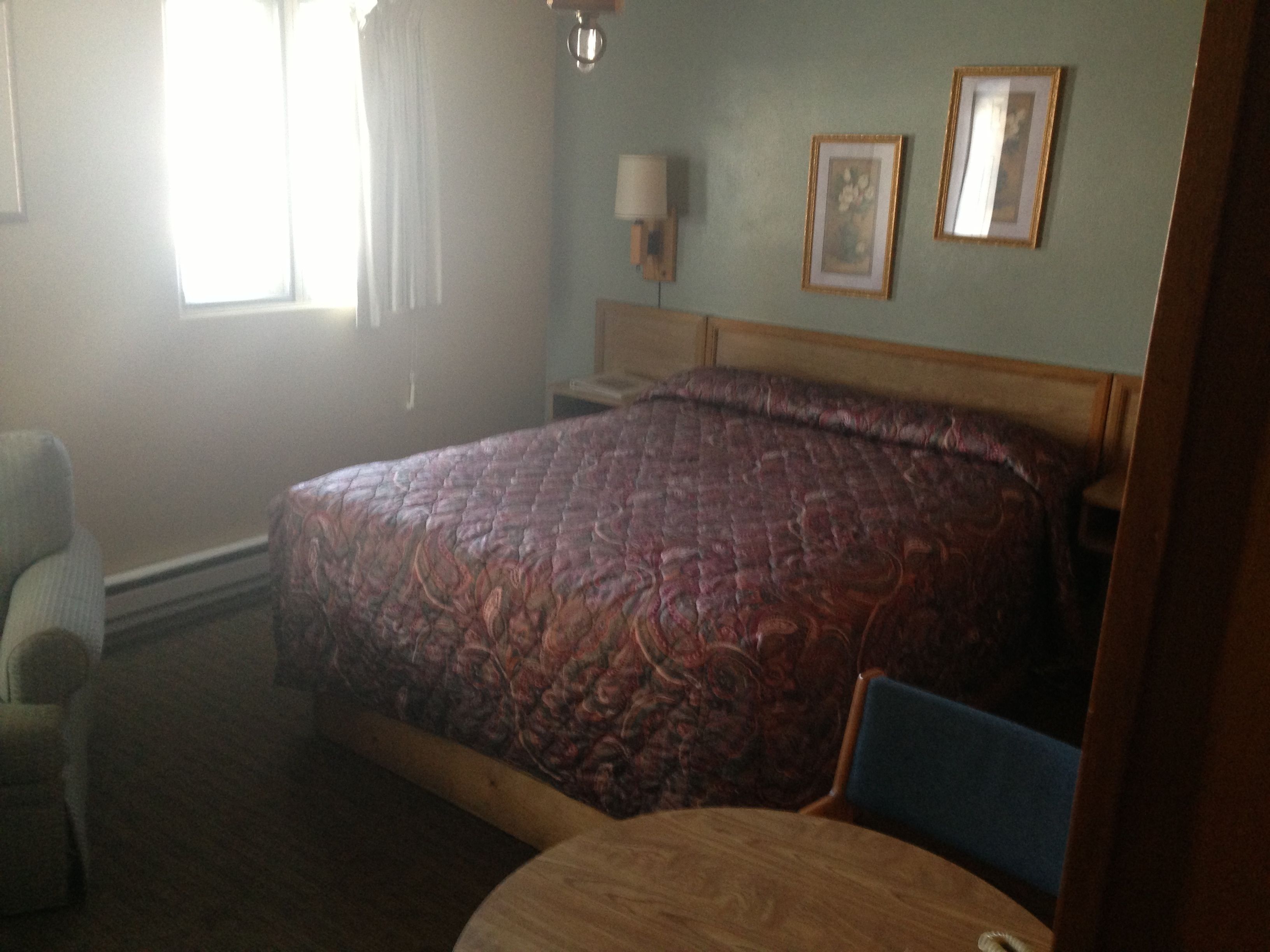 Une chambre d’hôtel avec un grand lit, une chaise, une table de chevet et une lampe.