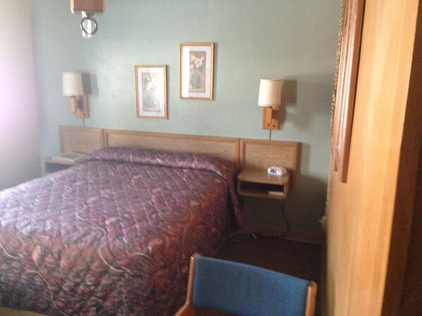 A hotel room with a large bed, two bedside tables, a chair, and two wall-mounted lamps.