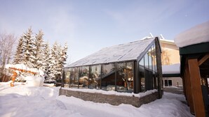 A modern building with a glass facade and a sloped roof, surrounded by snow. - Pike's Waterfront Lodge (Fairbanks)