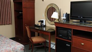 A hotel room with a bed, a desk with a chair, a television, a microwave, and a wardrobe.