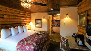 A wooden cabin room with a bed, a dining table, and a kitchen area. - Pike's Waterfront Lodge (Fairbanks)