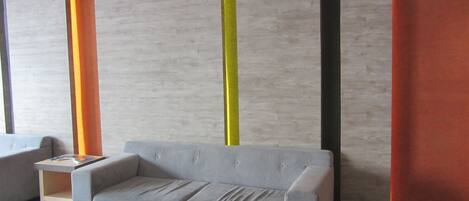 Una sala de estar moderna con un sofá gris, una mesita auxiliar y piso de madera.