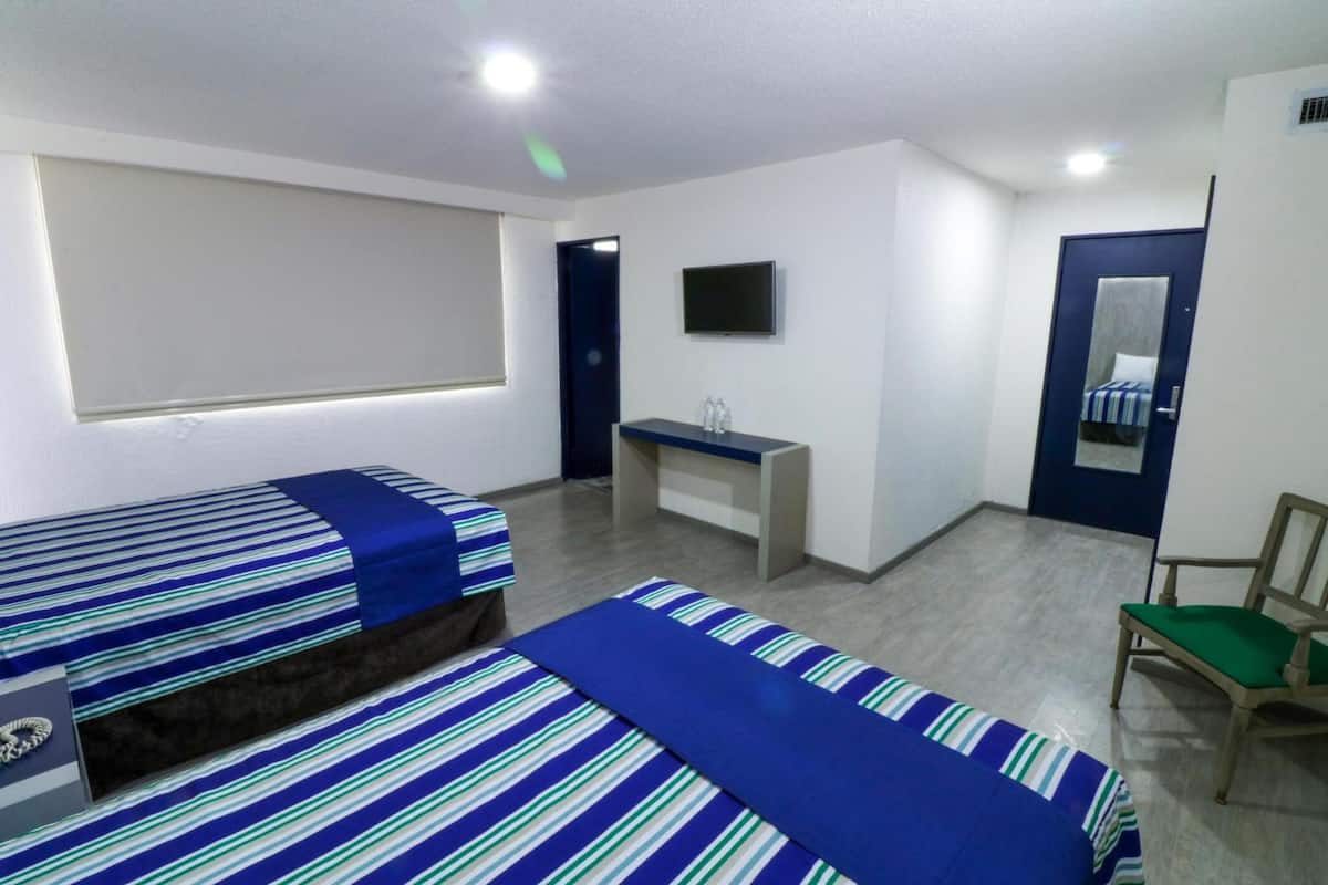 A room with two beds, a desk, a chair, a TV, and a mirror.