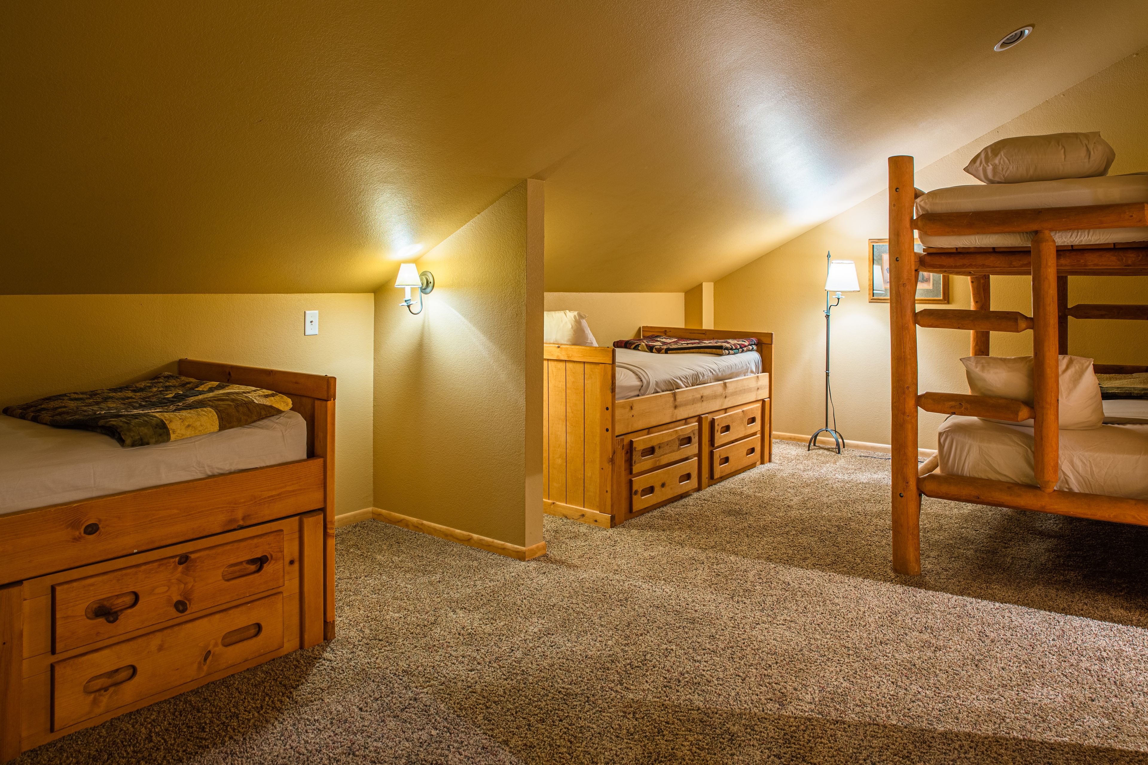 A room with bunk beds, a desk, and a lamp.