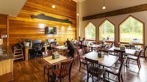 Un restaurante con paredes de madera, ventanas amplias y mesas y sillas dispuestas para comer.