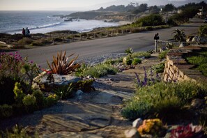 A coastal road with a sandy beach, rocky terrain, and various plants. - Cambria Shores Inn (Cambria)