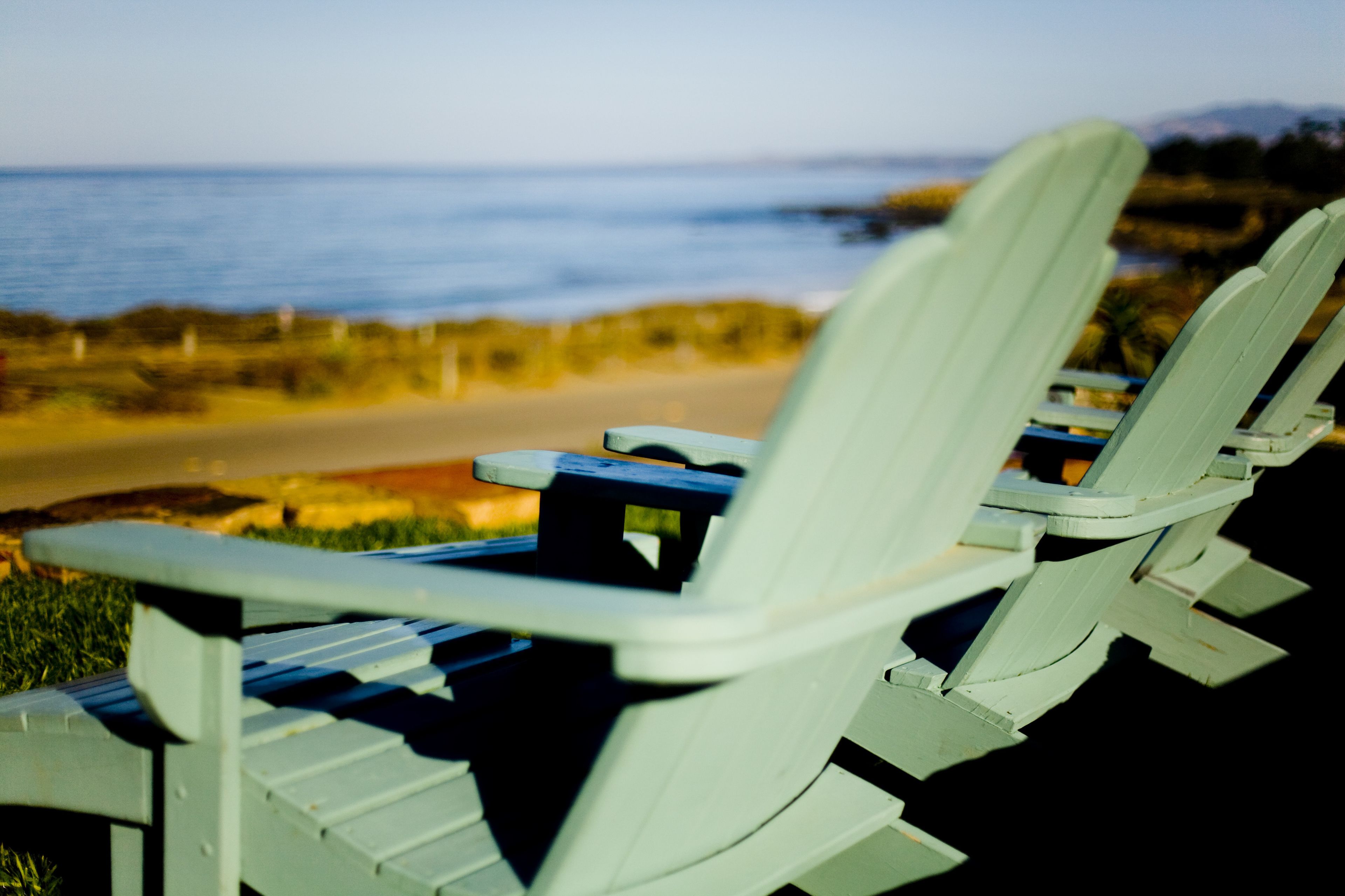 A row of white beach chairs with a view of the ocean and beach in the background.