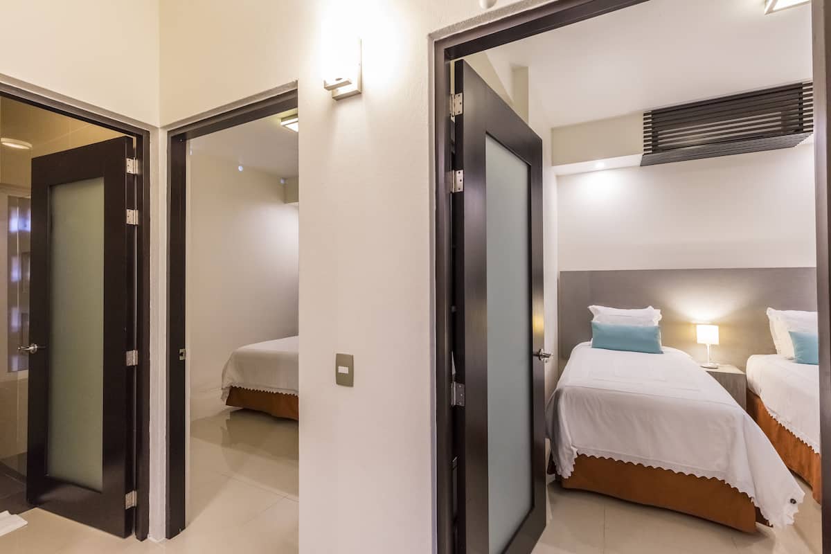 A hotel room with a bed, bedside table, and a lamp.