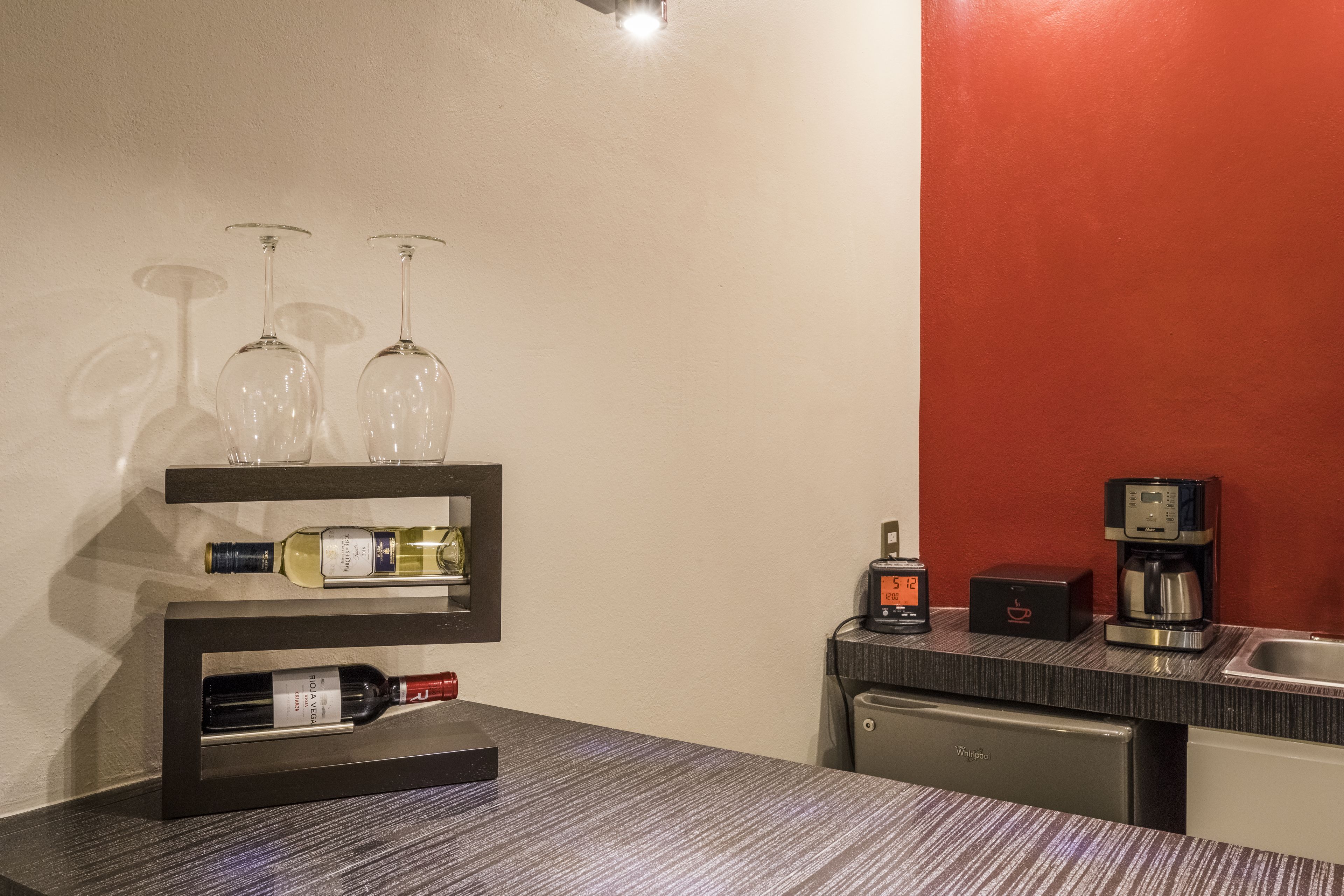 Una cocina con un espacio para vinos que contiene botellas y copas, una cafetera y un lavavajillas.