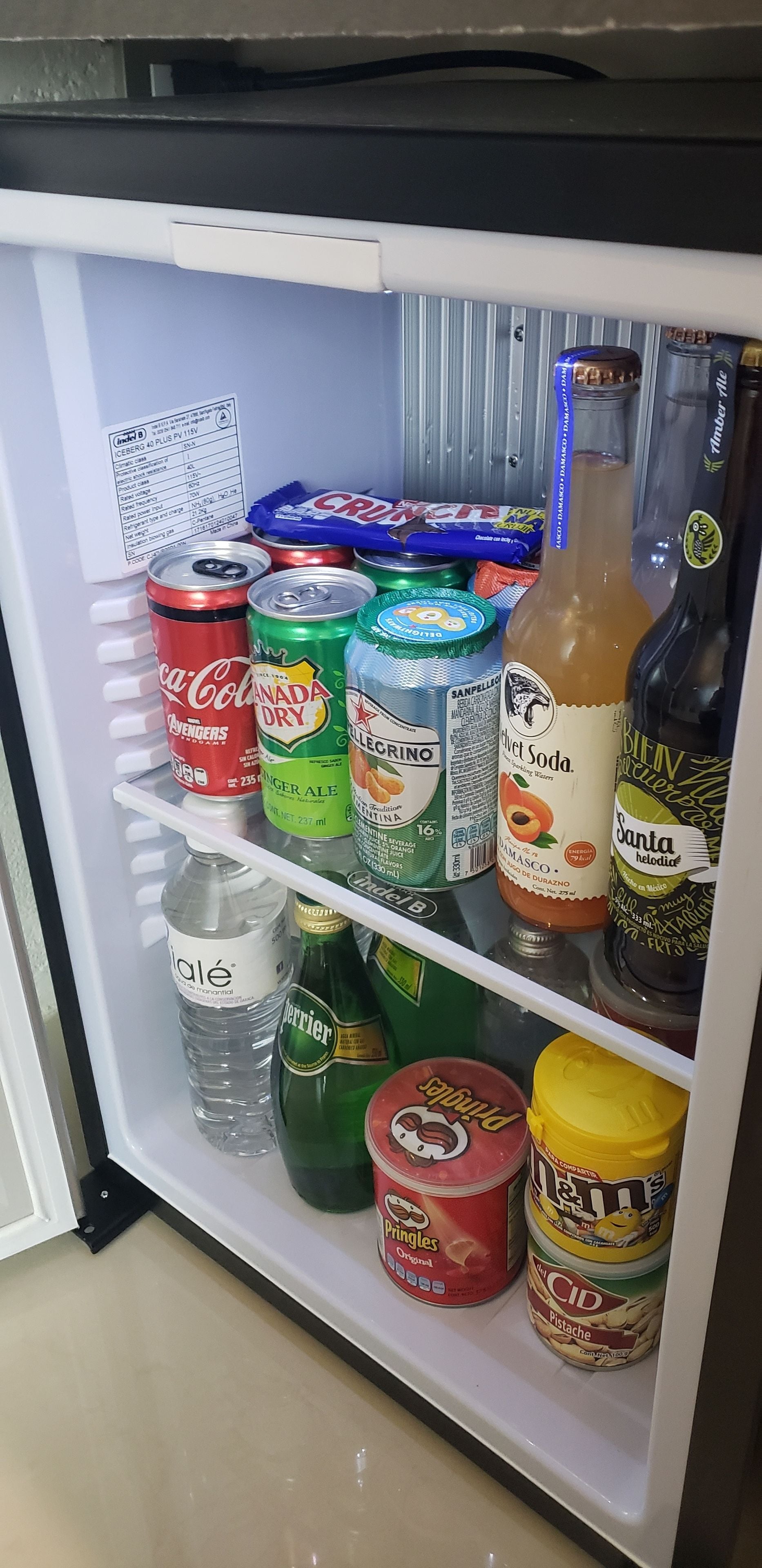 Geladeira com diversas bebidas, incluindo refrigerantes, cervejas e água.