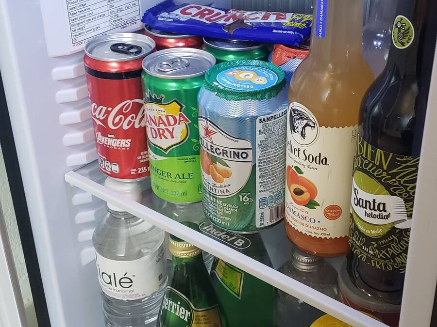 Geladeira com diversas bebidas, incluindo refrigerantes, cervejas e água.