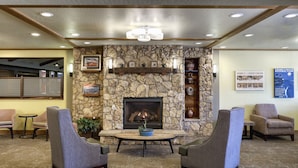 A lobby with a stone fireplace, comfortable seating, and informational posters.