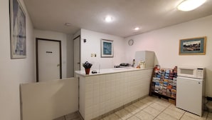 A small kitchenette with a microwave, a refrigerator, a sink, and a countertop with a potted plant.