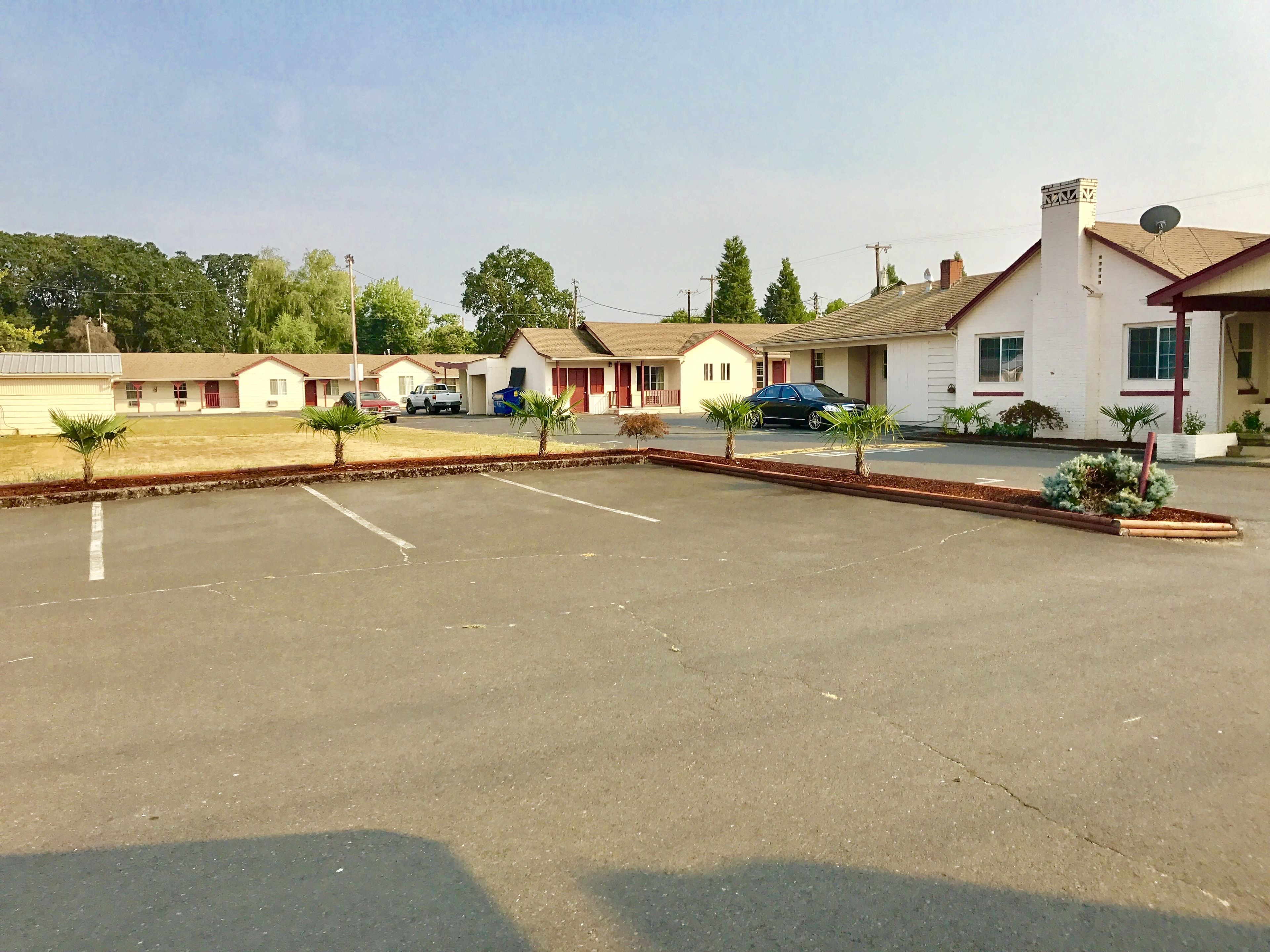 A parking lot with several single-story buildings, each with a red door and a small attached garage.