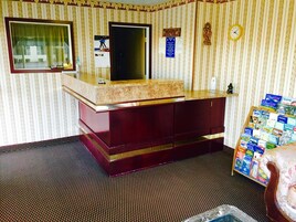 A hotel room with a marble vanity, a large window, a welcome sign, a clock, and a bulletin board with travel brochures.
