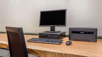A wooden desk with a computer setup including a monitor, keyboard, and printer.