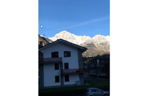A two-story building with a balcony, set against a backdrop of snow-capped mountains. - Hotel Edelweiss (Pre-Saint-Didier)