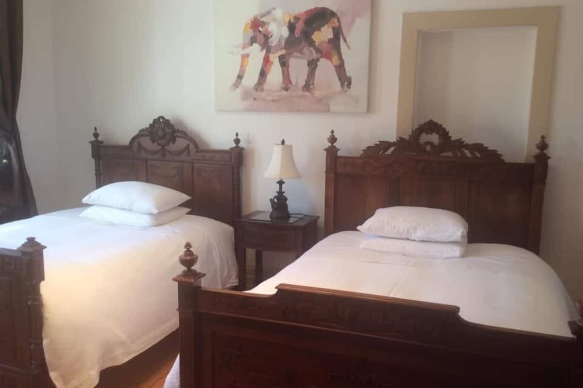 Ein Doppelzimmer mit zwei hölzernen Betten, jeweils mit passendem Nachttisch und Lampe.