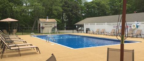 Une piscine avec des chaises longues et un espace abrité.