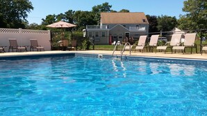 En swimmingpool med liggestole og et hus i baggrunden.
