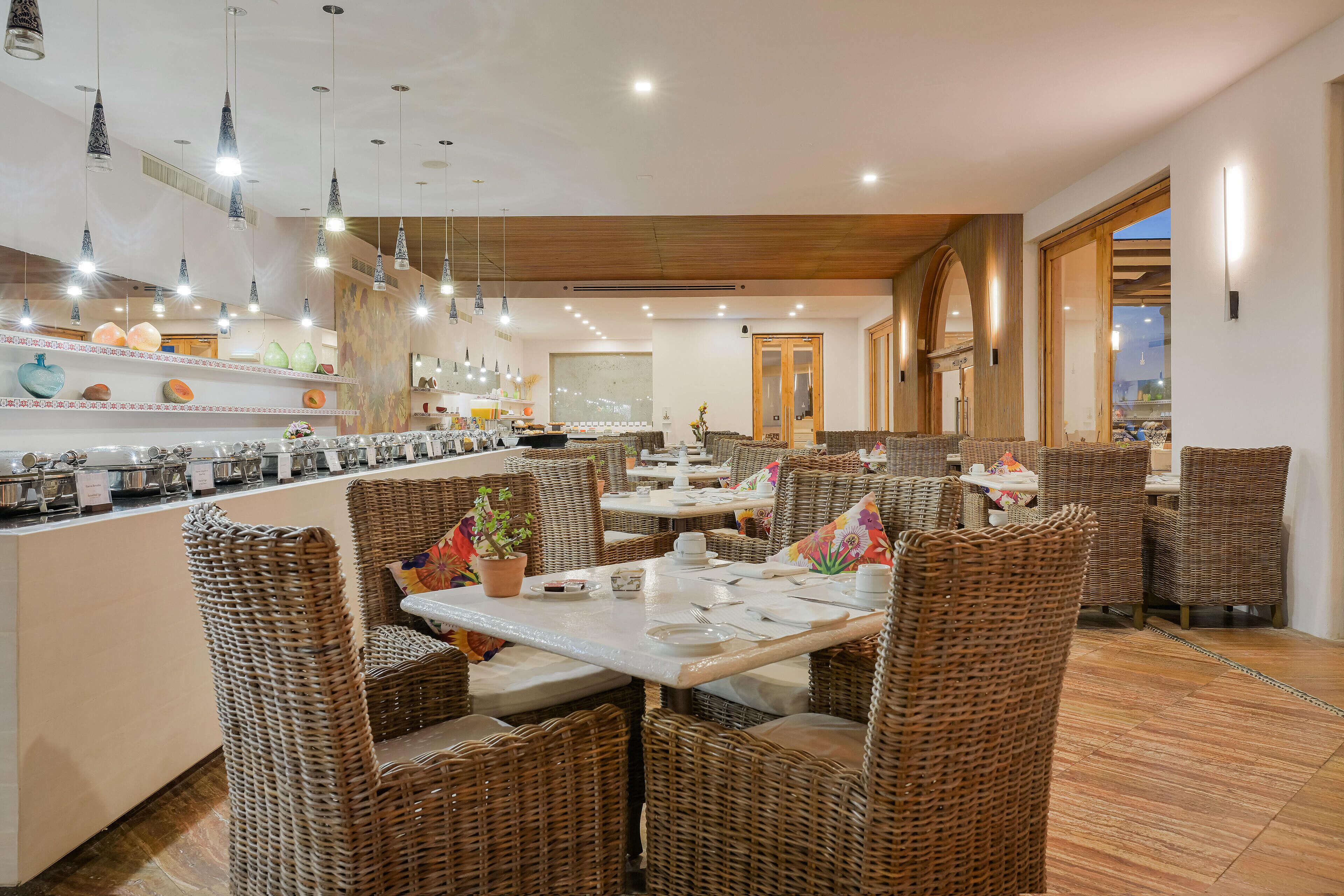 A restaurant with wicker furniture, a bar area, and pendant lighting.