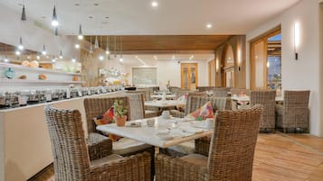 A restaurant with wicker furniture, a bar area, and pendant lighting.