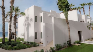 Un bâtiment moderne à la façade blanche, entouré de palmiers et d’une pelouse bien entretenue.