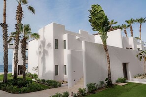 Un bâtiment moderne à la façade blanche, entouré de palmiers et d’une pelouse bien entretenue.