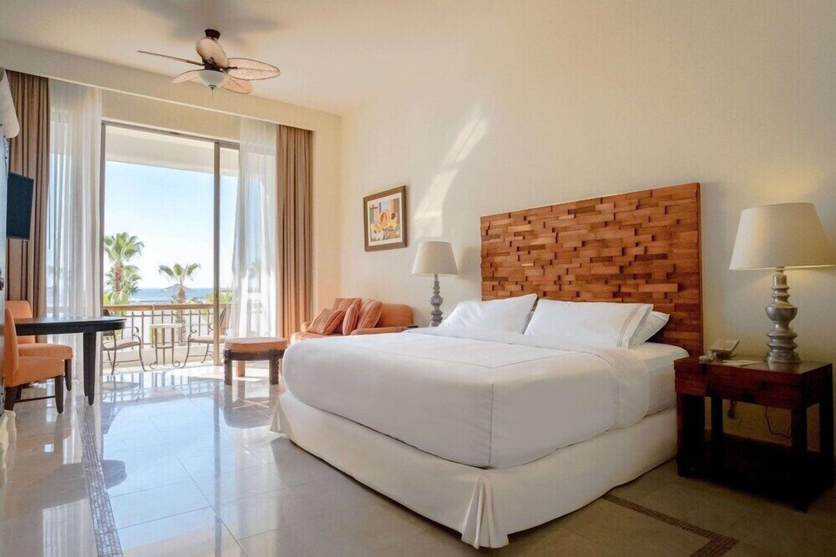 Une chambre d’hôtel avec un grand lit, un balcon avec vue, un bureau et une chaise.