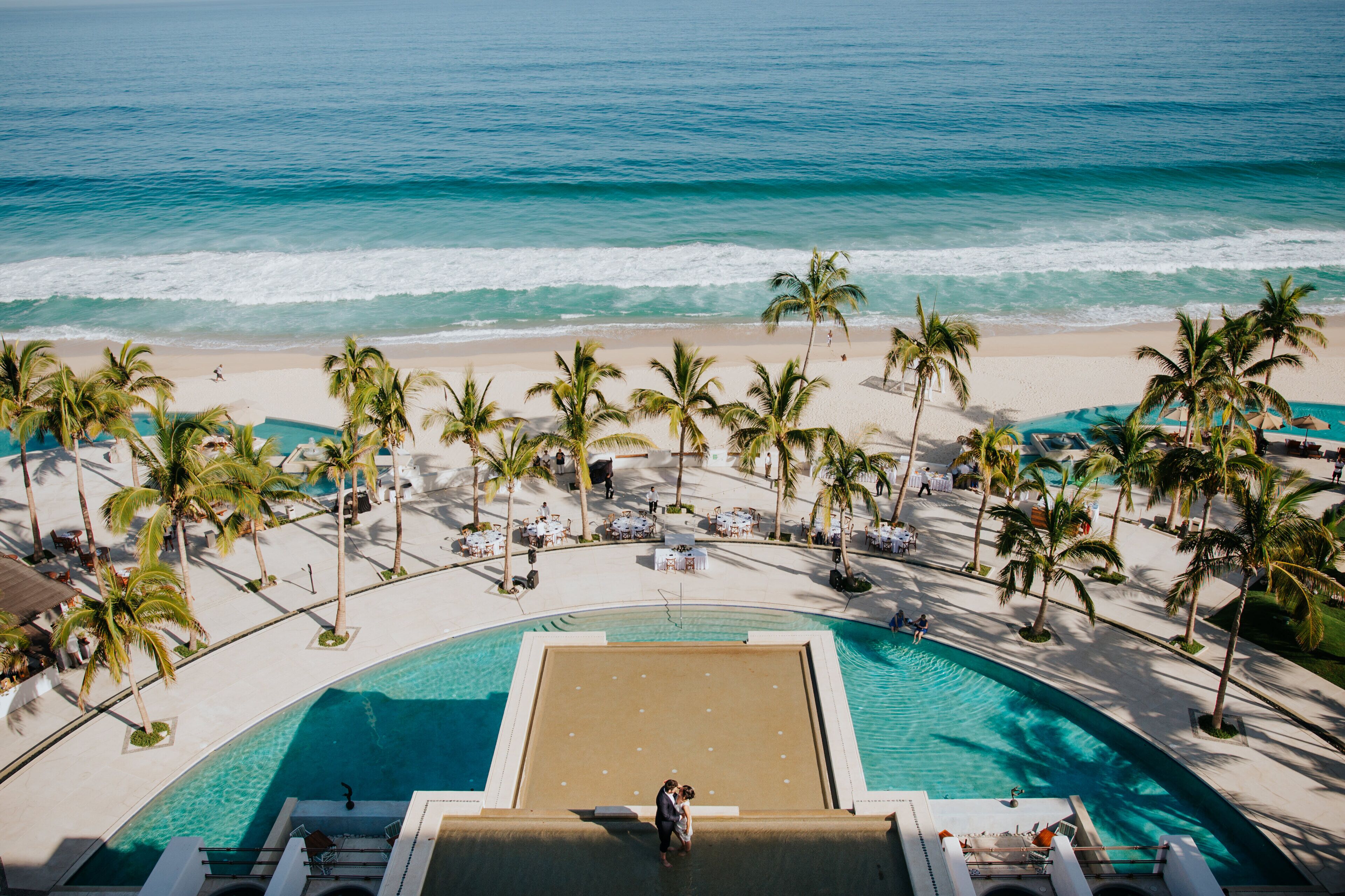 Un resort con piscina, playa y palmeras.