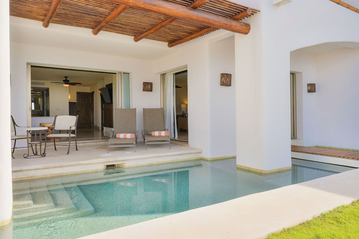 Ein Poolbereich mit zwei Liegestühlen, einem Tisch und einem Deckenventilator.