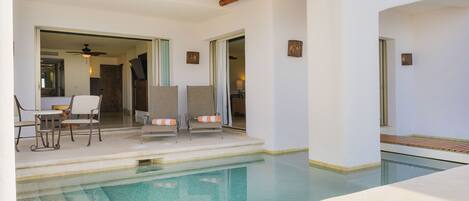 Un área de piscina con dos sillas de descanso, una mesa y un ventilador de techo.