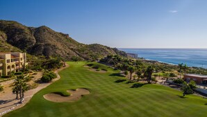 Un parcours de golf offrant une vue sur l’océan et les montagnes.