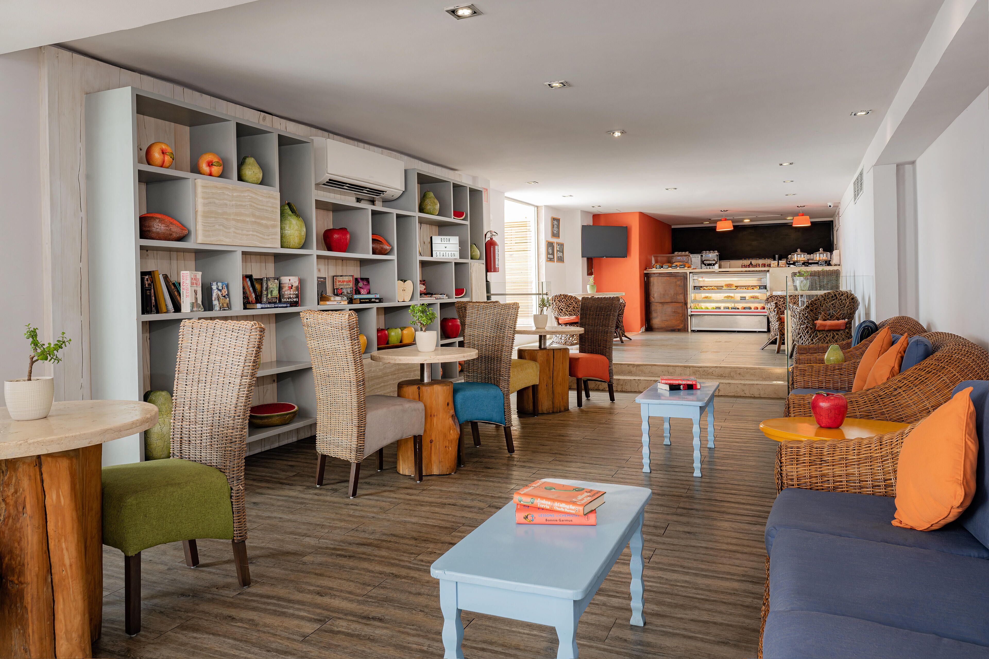 A modern living area with a sofa, chairs, a coffee table, and a bookshelf filled with books and decorative items.