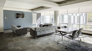 A modern conference room with a grey patterned sofa, a white table, and black chairs. - University of Calgary - Seasonal Residence (Calgary)