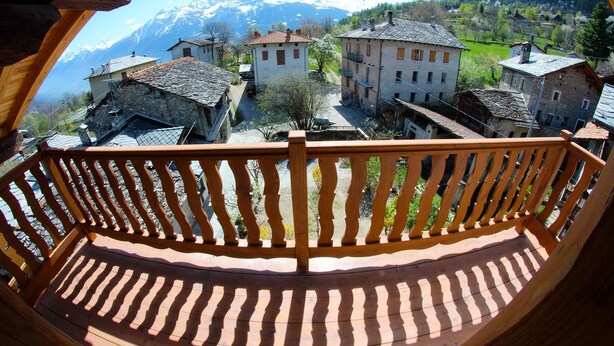 Un balcón de madera con vistas a un pueblo y montañas.