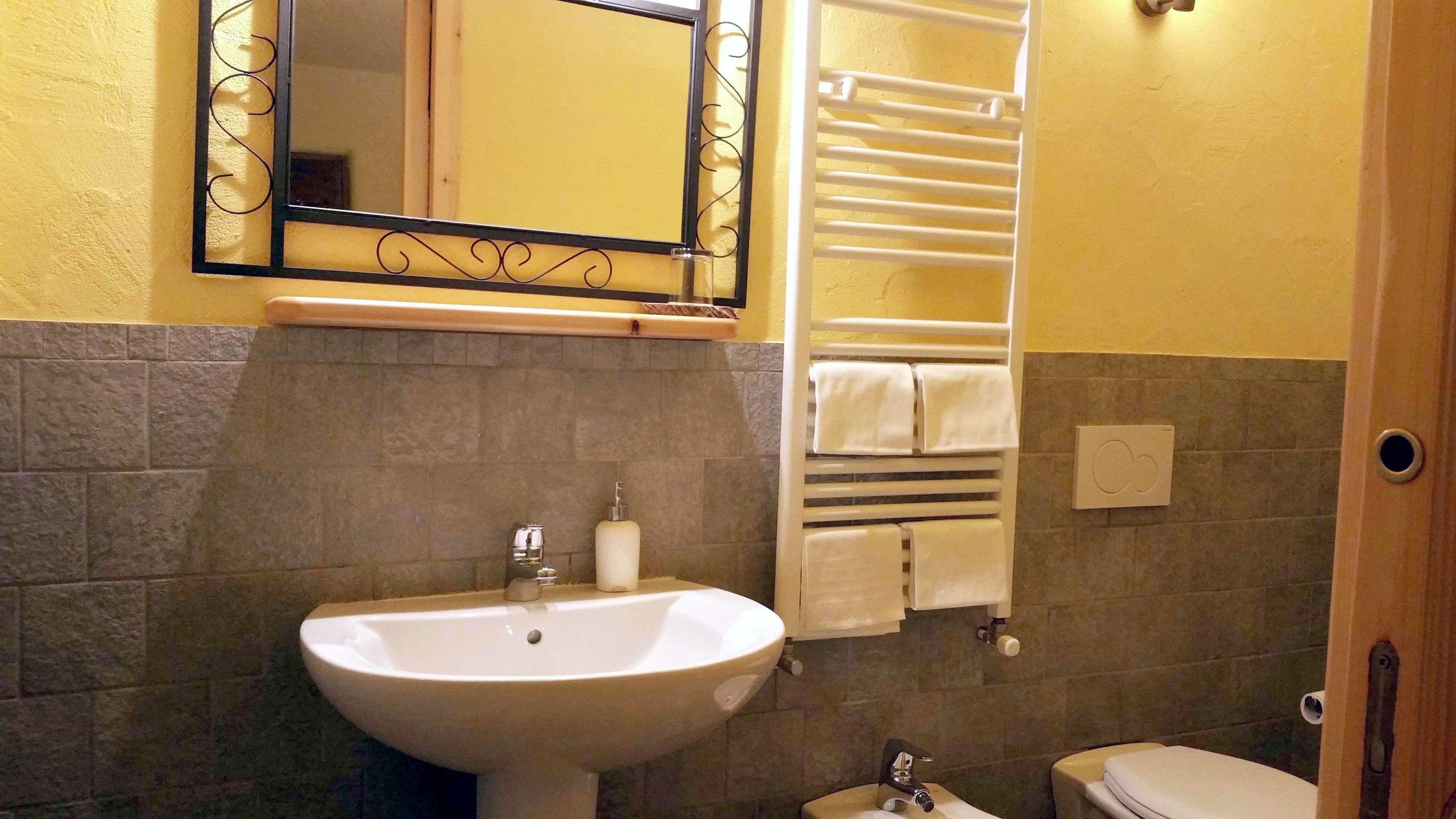 Une salle de bain équipée d’un lavabo, d’un miroir, d’un porte-serviettes et de toilettes.