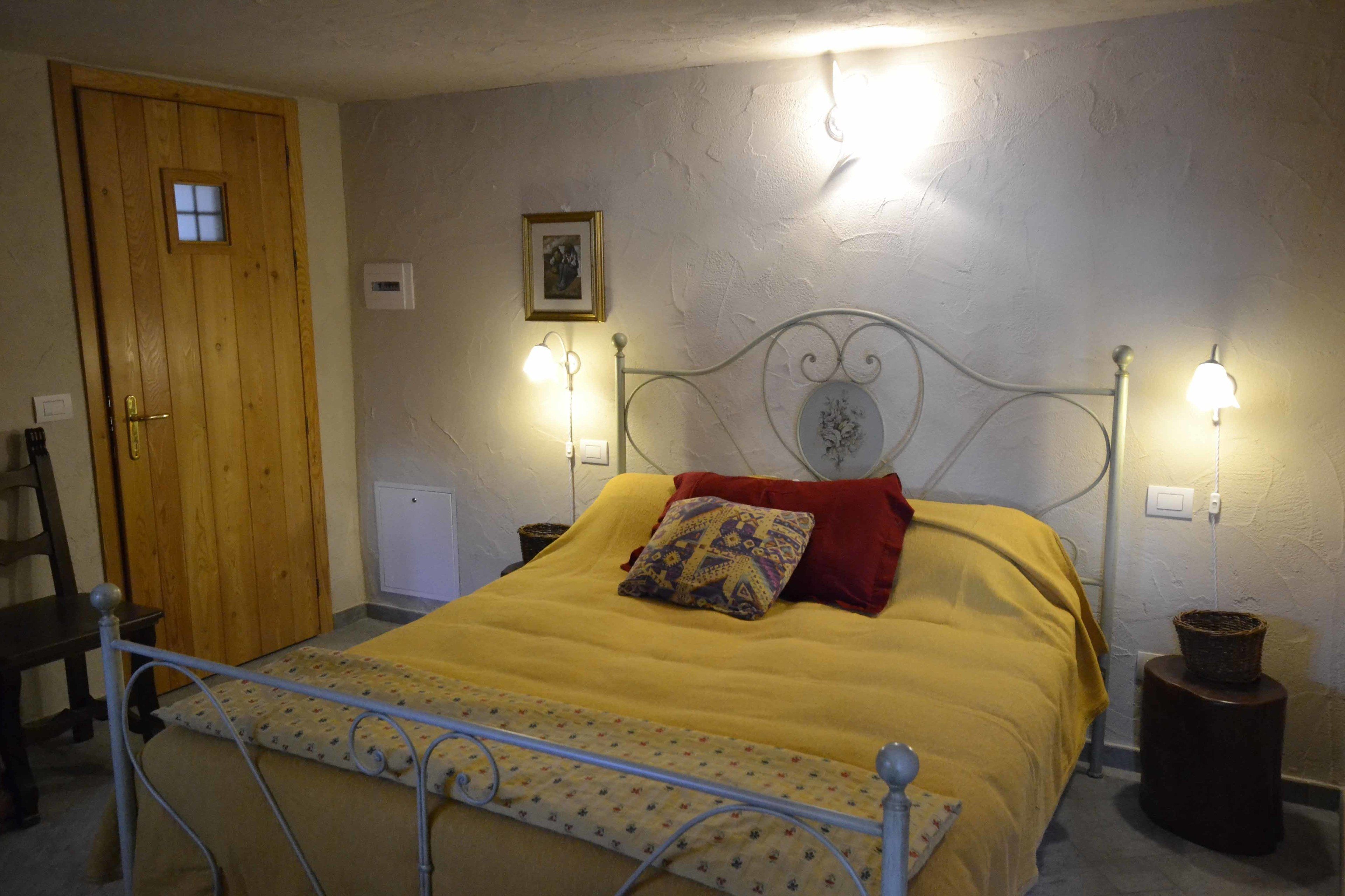 Een slaapkamer met een bed, een houten deur, een aan de muur hangend schilderij en twee bedlampen.