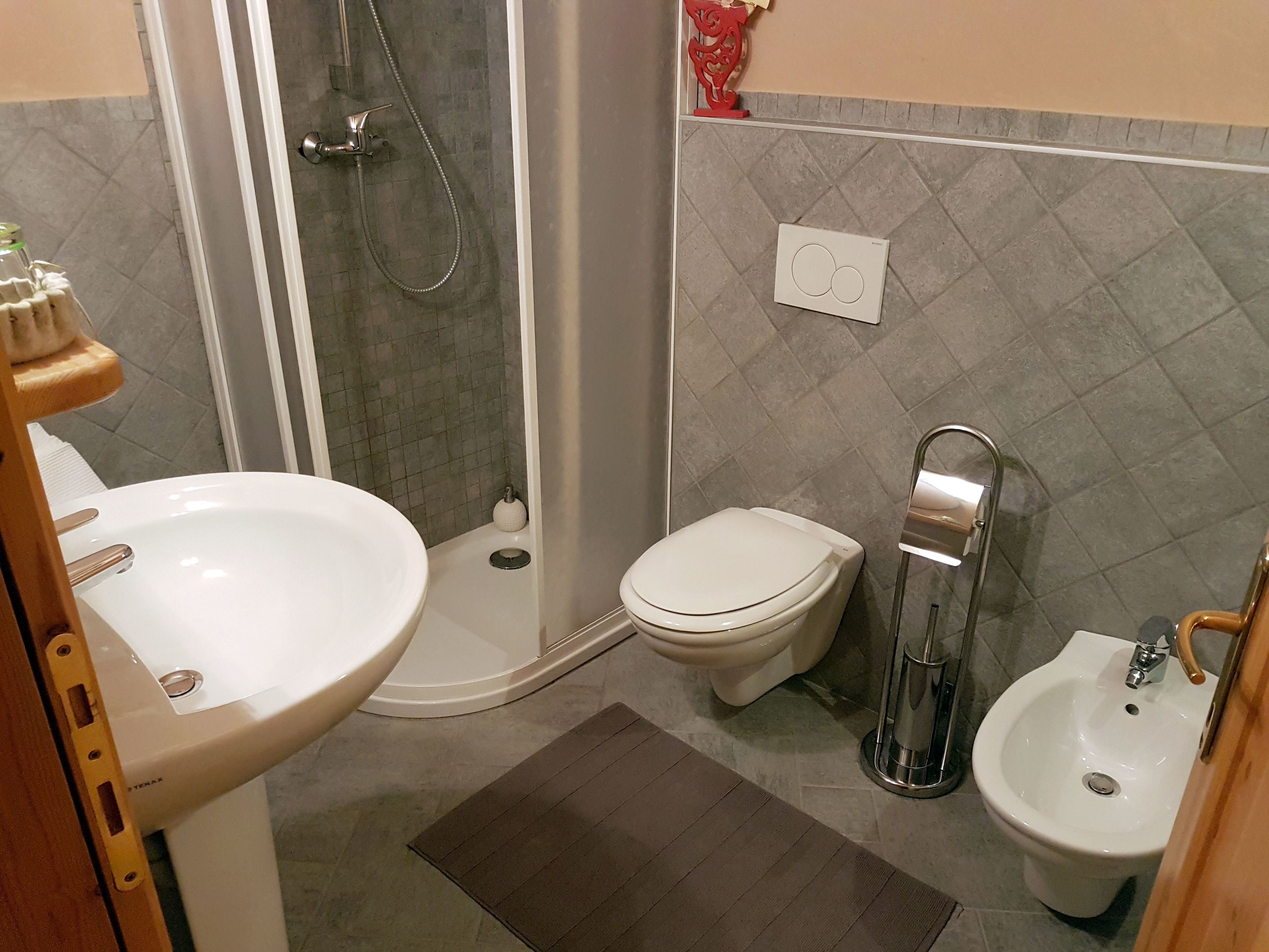 Une salle de bain équipée d’une douche, de toilettes, d’un bidet et d’un lavabo.