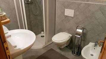 Une salle de bain équipée d’une douche, de toilettes, d’un bidet et d’un lavabo.