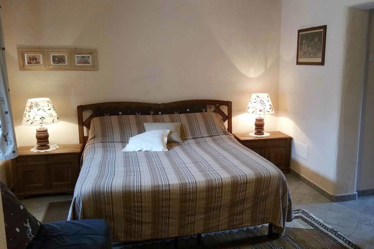A neatly made bed with striped bedding, two bedside lamps, and a framed picture on the wall.