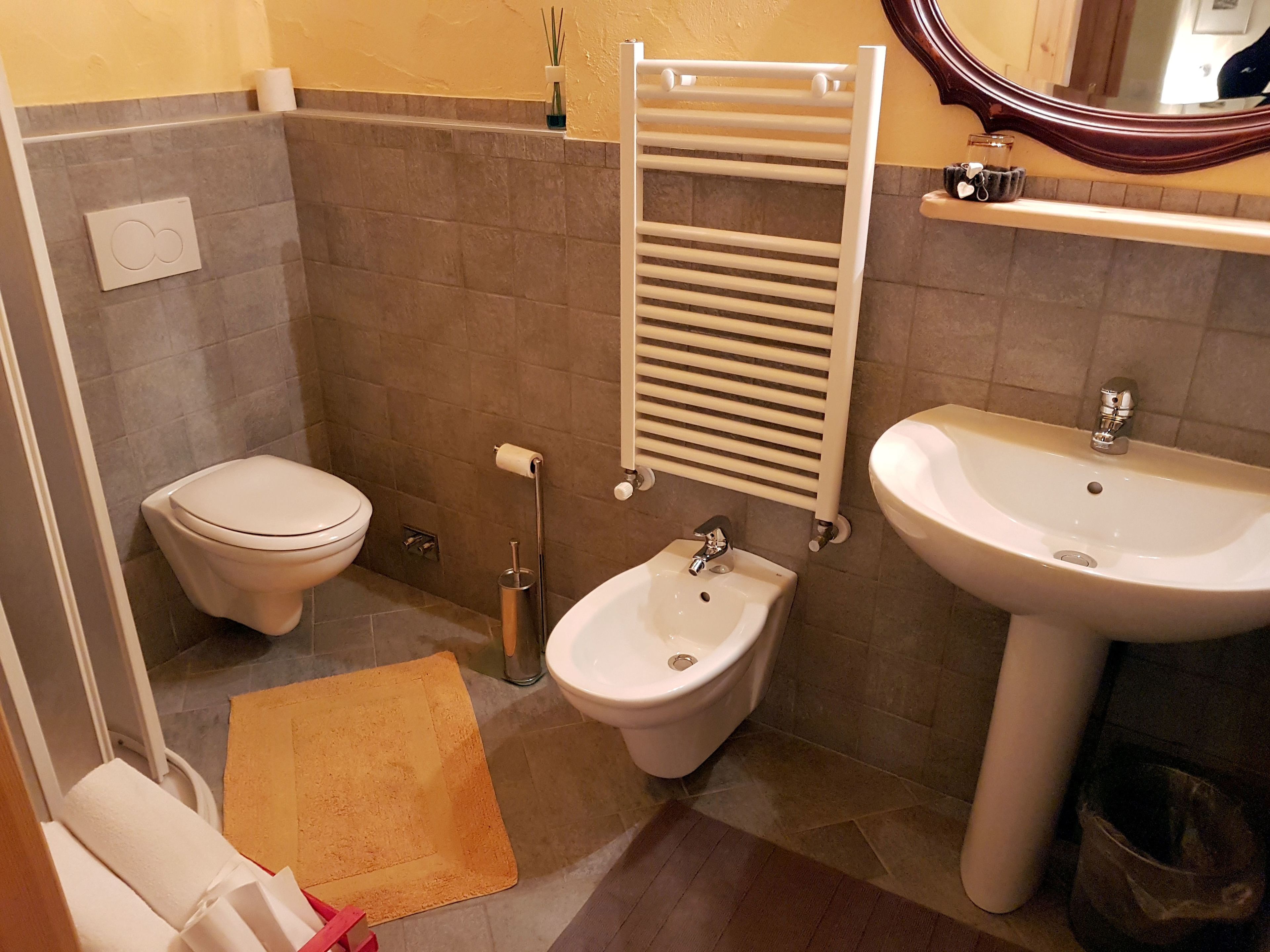 Un bagno con il water, bidet, lavandino, portasciuga e uno specchio.