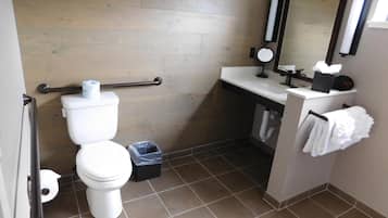 A compact bathroom with a toilet, a sink, a mirror, and a towel rack.