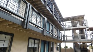 A multi-story building with a modern architectural design, featuring balconies, large windows, and a central staircase. - Wave Street Inn (Monterey)
